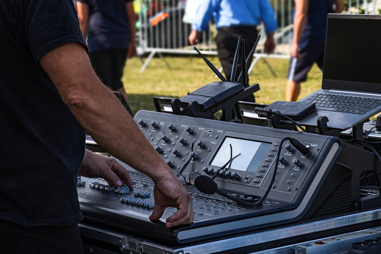 Audio engineer operates sound mixer for outdoor concert setup. Technology and music come together.